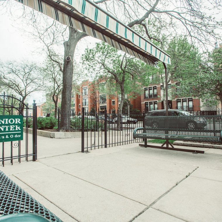 Black metal gate, green metal benches and green sign that states 