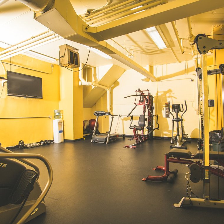 Angled view of the workout area depicting elipticals and wall mounted television