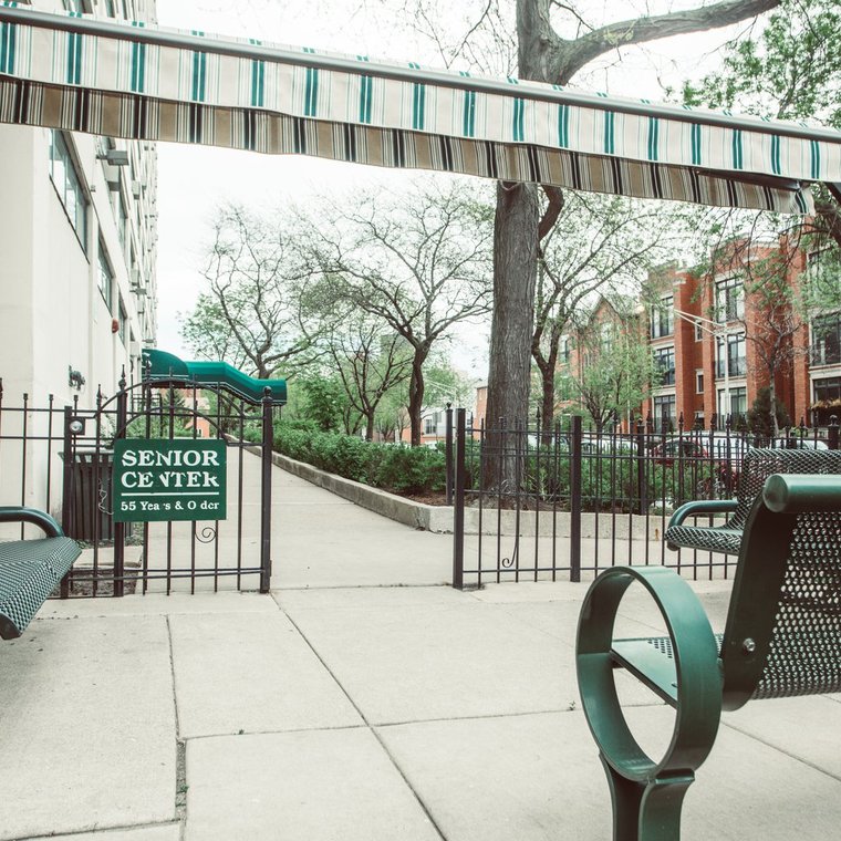 Senior Center area with green metal benches outside in a gated area